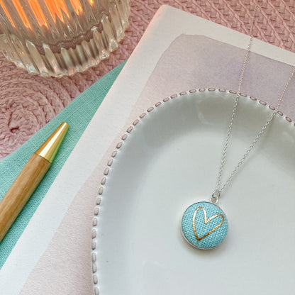 Mint aqua necklace with a heart-shaped pendant on a white plate