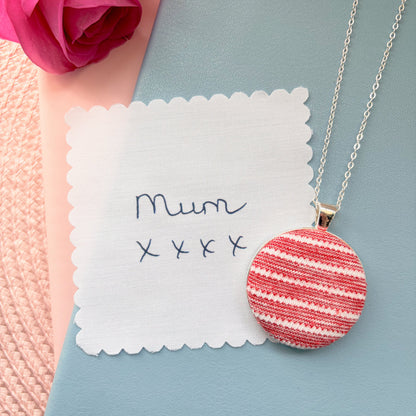 Necklace with a red and white striped pendant with 'Mum' and 'xxx' on a blue surface.