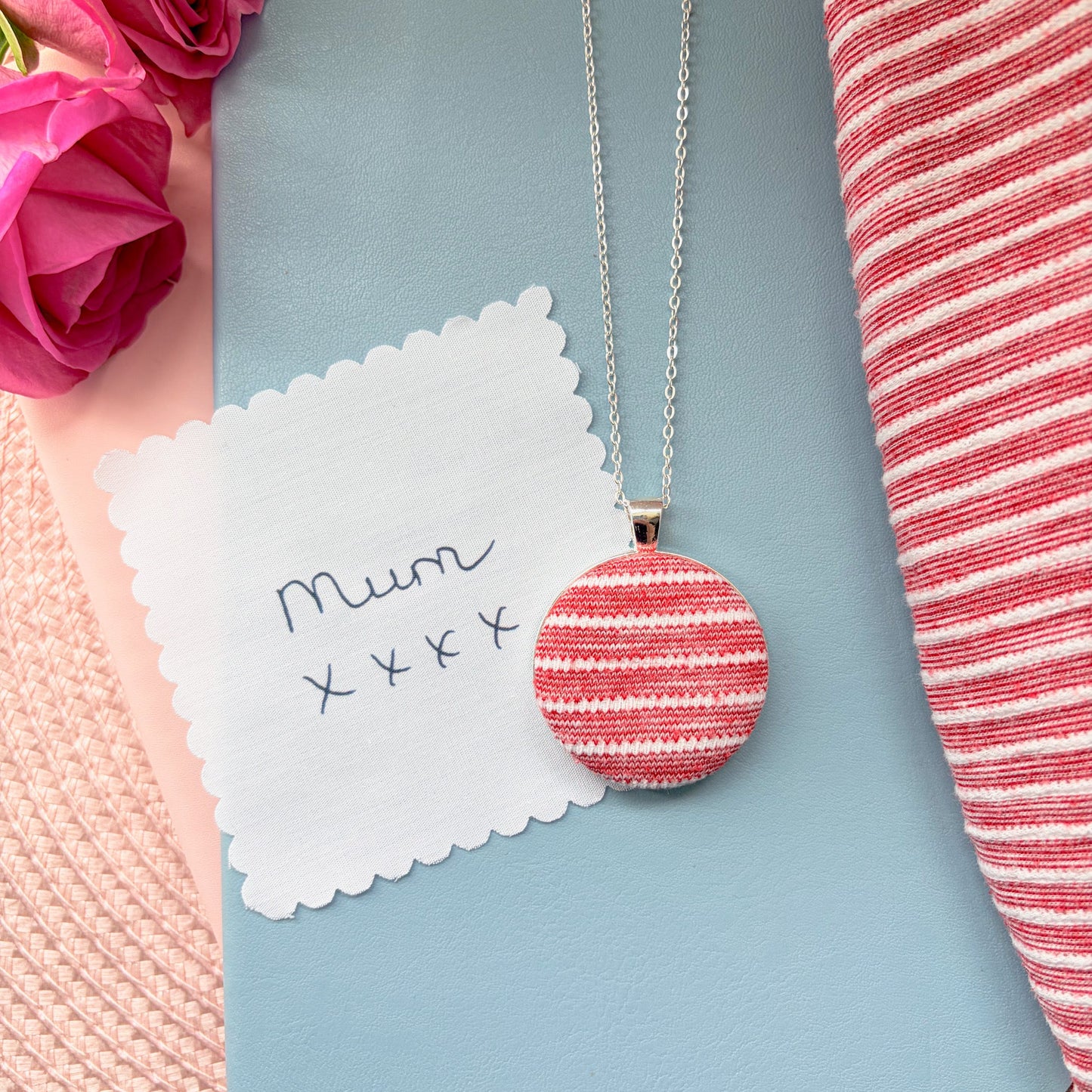 Necklace with a red and white striped pendant with 'Mum' and 'xxx' text, surrounded by pink flowers and a red and white striped fabric.