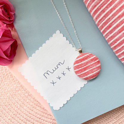 Necklace with a red and white striped pendant with 'Mum x x x' text, surrounded by pink flowers and fabric.