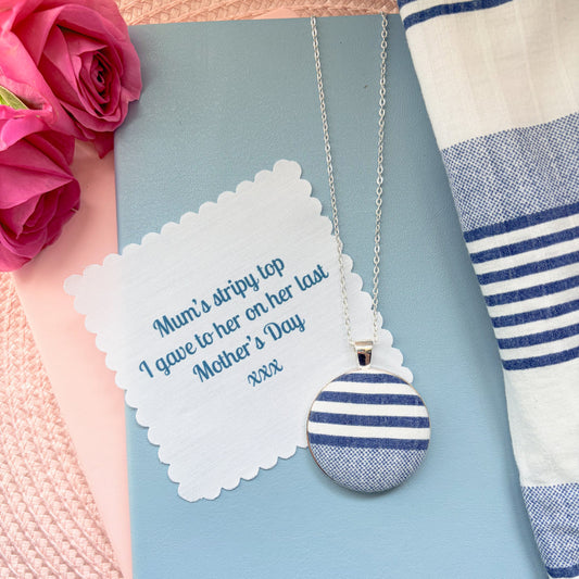 Necklace with striped pendant with fabric message, surrounded by pink flowers and striped fabric fabric