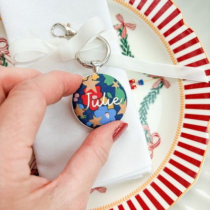 Personalised keyring tied on a velvet ribbon, around a serviette as a place setting, made with blue Liberty floral fabric, printed with Julie in gold 