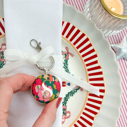 Personalised table place setting made with Liberty green floral fabric, printed with a gold S, thread on a white velvet ribbon and tied around a napkin on Christmas plates
