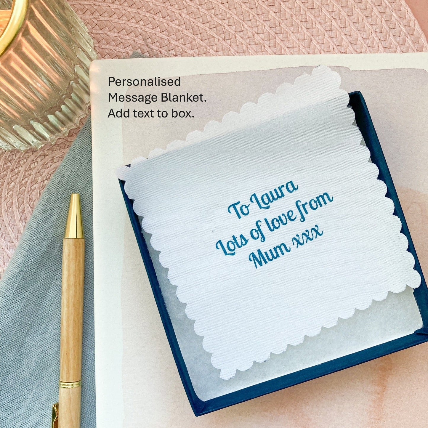 Personalised message blanket with text on a pink surface with a pen.