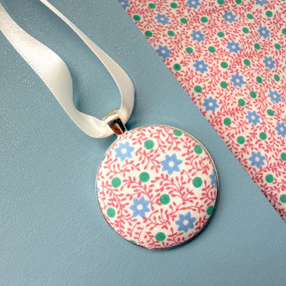 Floral pyjamas memory keepsake, thread on a ribbon, set on a blue notebook 