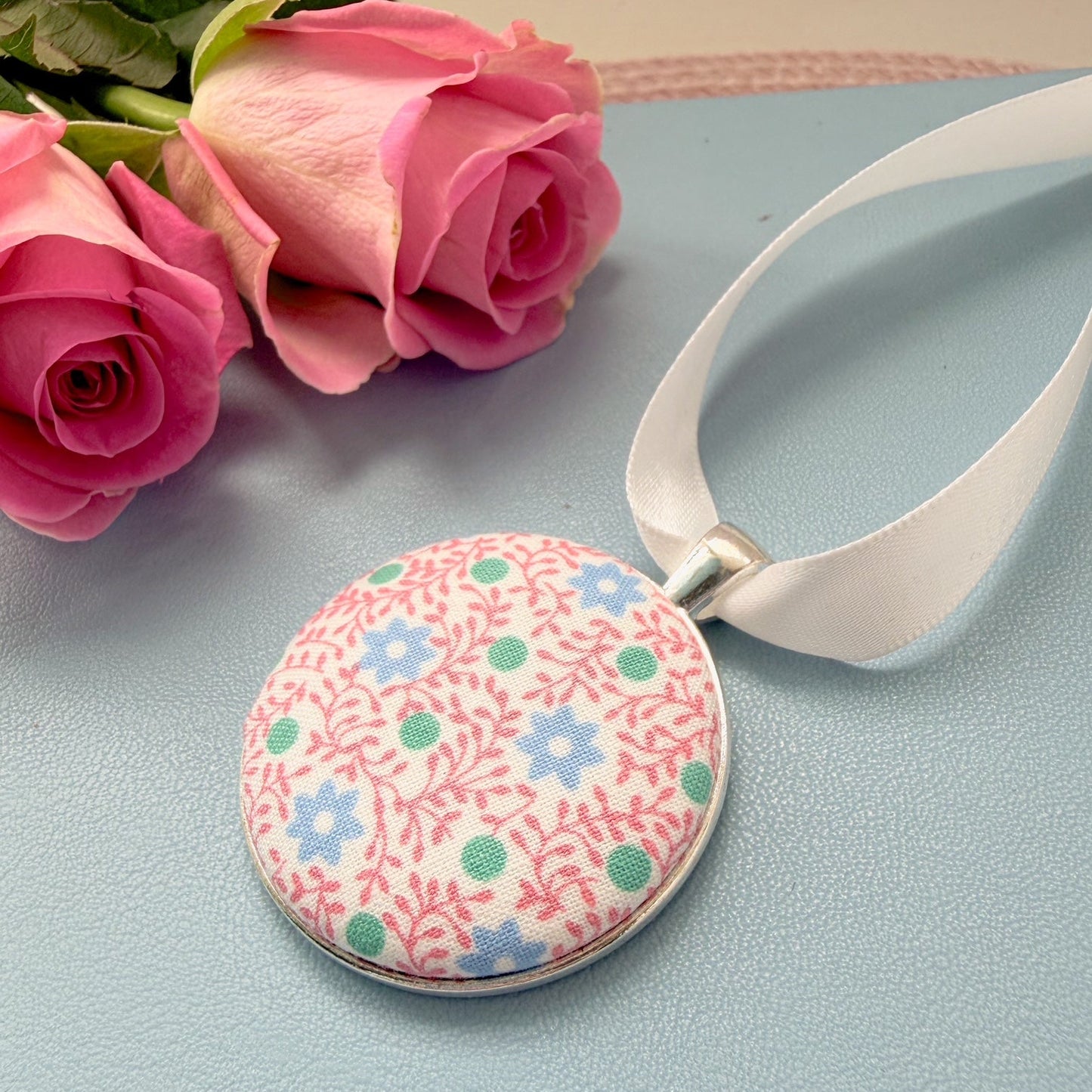 Floral pyjamas memory keepsake, thread on a ribbon, set on a blue notebook with a rose