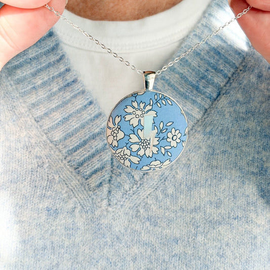 Secret Mantra necklace with a silver lightning printed on a Liberty blue floral fabric, thread on a silver chain and worn with a pale blue jumper