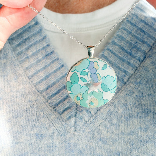 Secret Mantra necklace with a silver star printed on a Liberty mint green & lilac floral fabric, thread on a silver chain and worn with a pale blue jumper