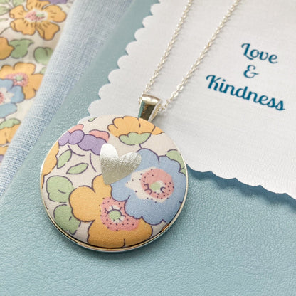 Yellow & lilac floral necklace with a silver foil heart on a blue book