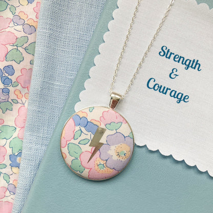 Pastel floral Liberty necklace with a lightning design and a fabric message saying Strength & Courage