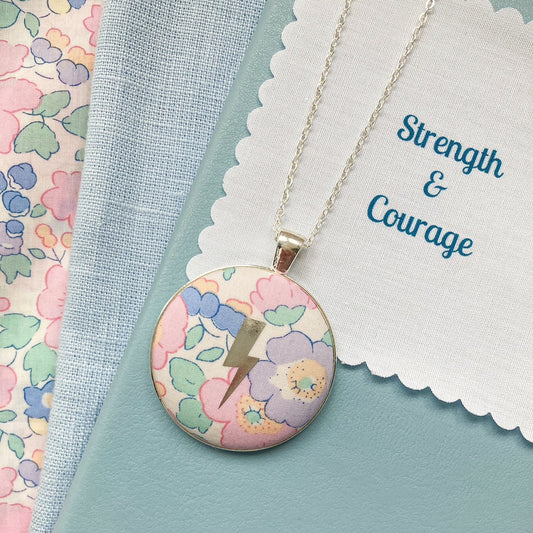 Pastel floral Liberty necklace with a lightning design and a fabric message saying Strength & Courage