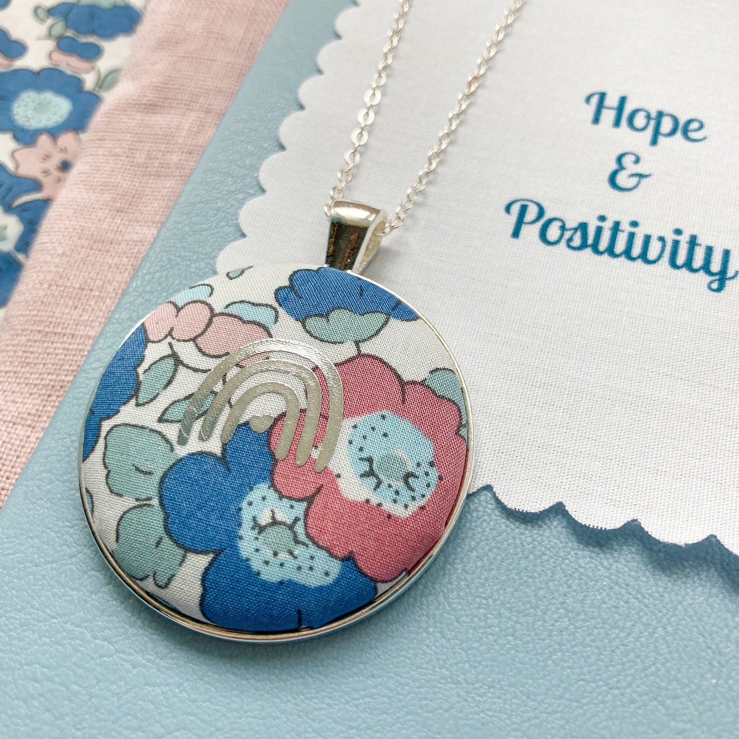 Floral pendant necklace with a fabric message saying 'Hope & Positivity'