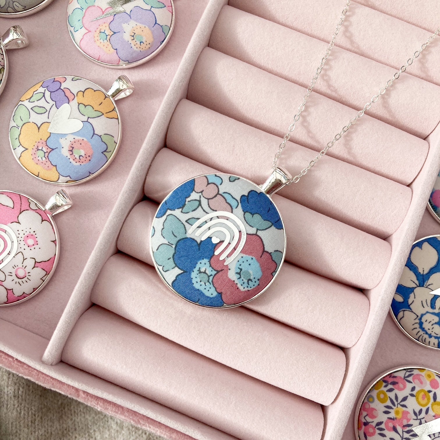 Colorful floral pendant necklaces in a pink jewelry box