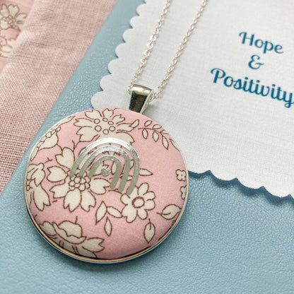 Necklace with a pink floral pendant and a fabric message with 'Hope & Positivity' text.