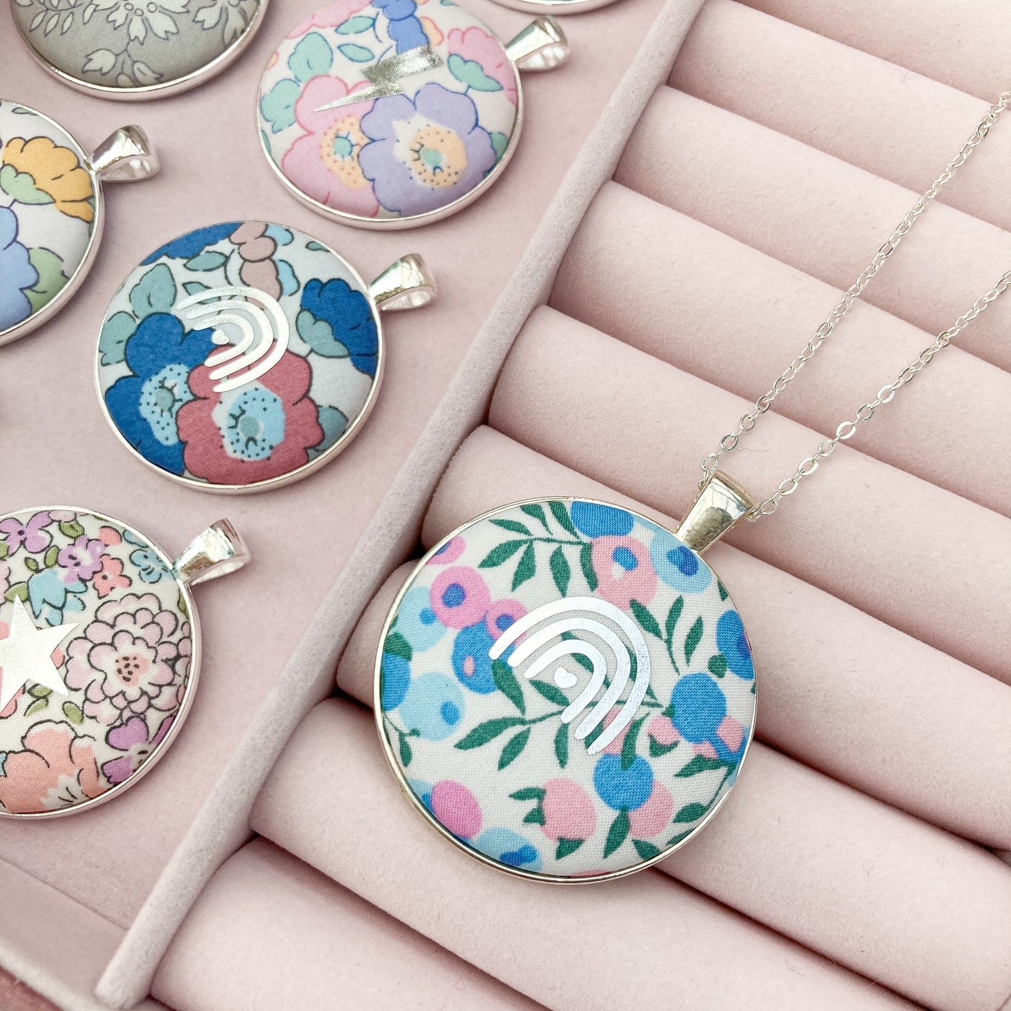 Colorful floral pendants on a pink jewelry box