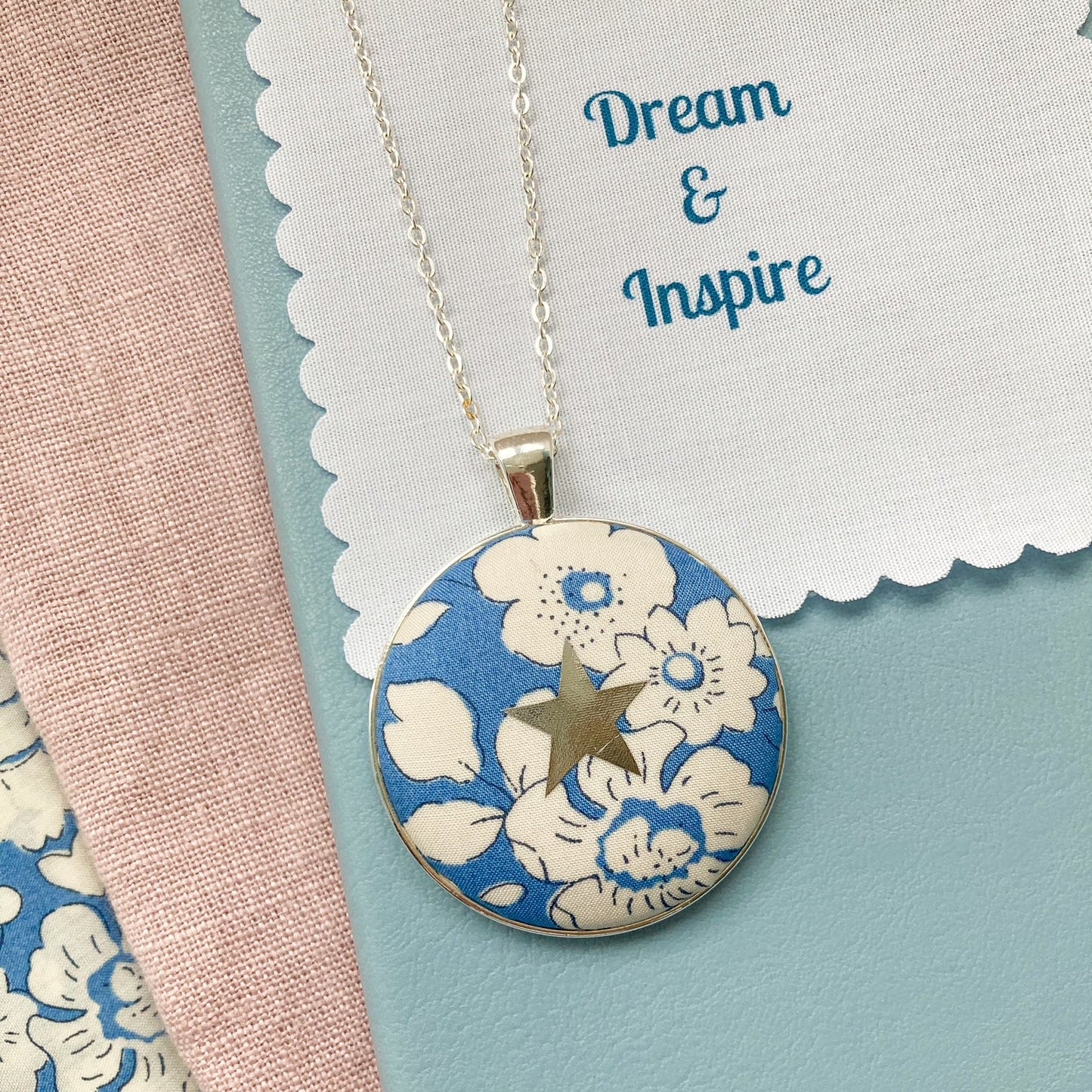 Blue floral necklace with a silver star and a fabric message saying "Dream & Inspire"