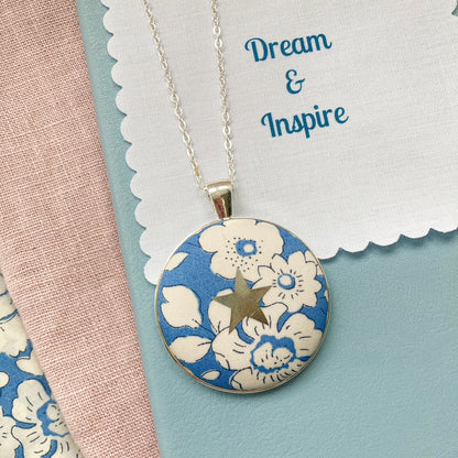 Blue floral necklace with a silver star and a fabric message saying "Dream & Inspire"