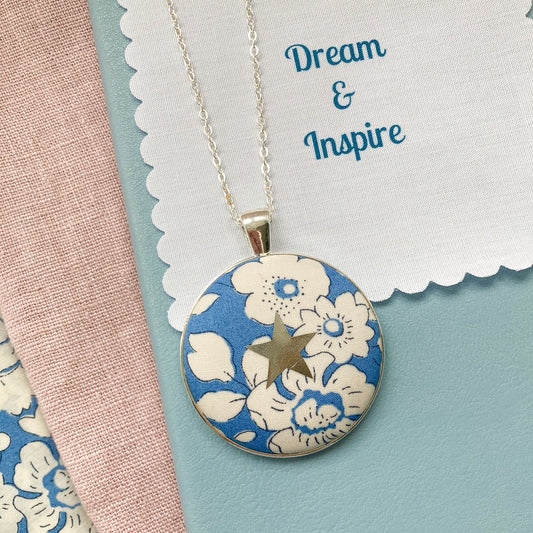 Blue floral necklace with a silver star and a fabric message saying "Dream & Inspire"
