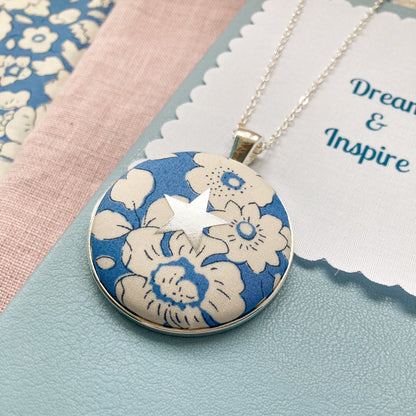 Blue flowery necklace with star design on a blue book