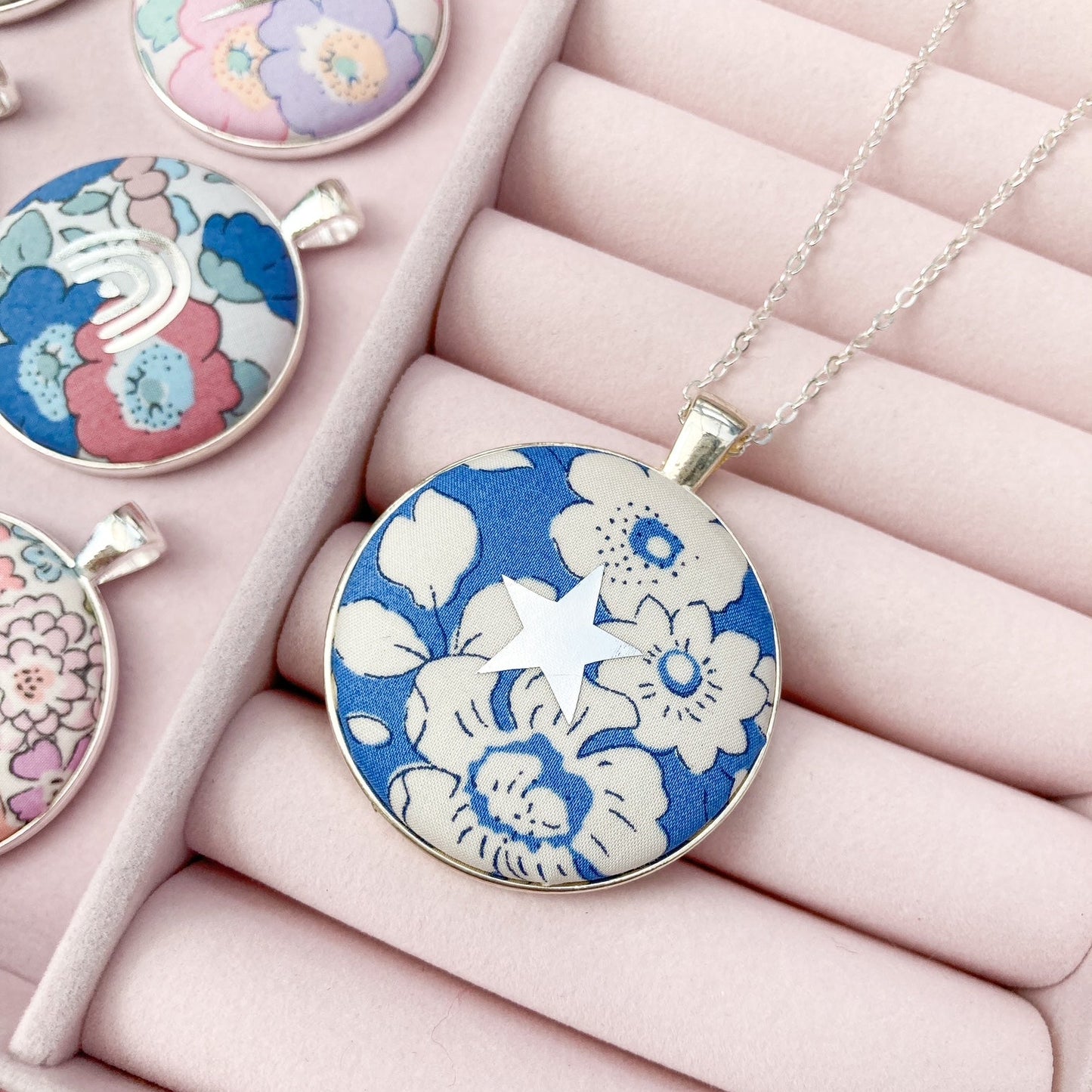 Blue Liberty floral necklace with a silver star in a pink jewellery box