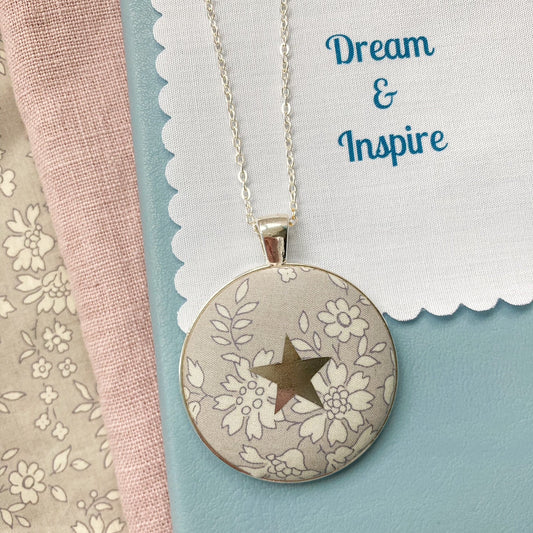 Grey floral necklace with a star design and a fabric message saying "Dream & Inspire"
