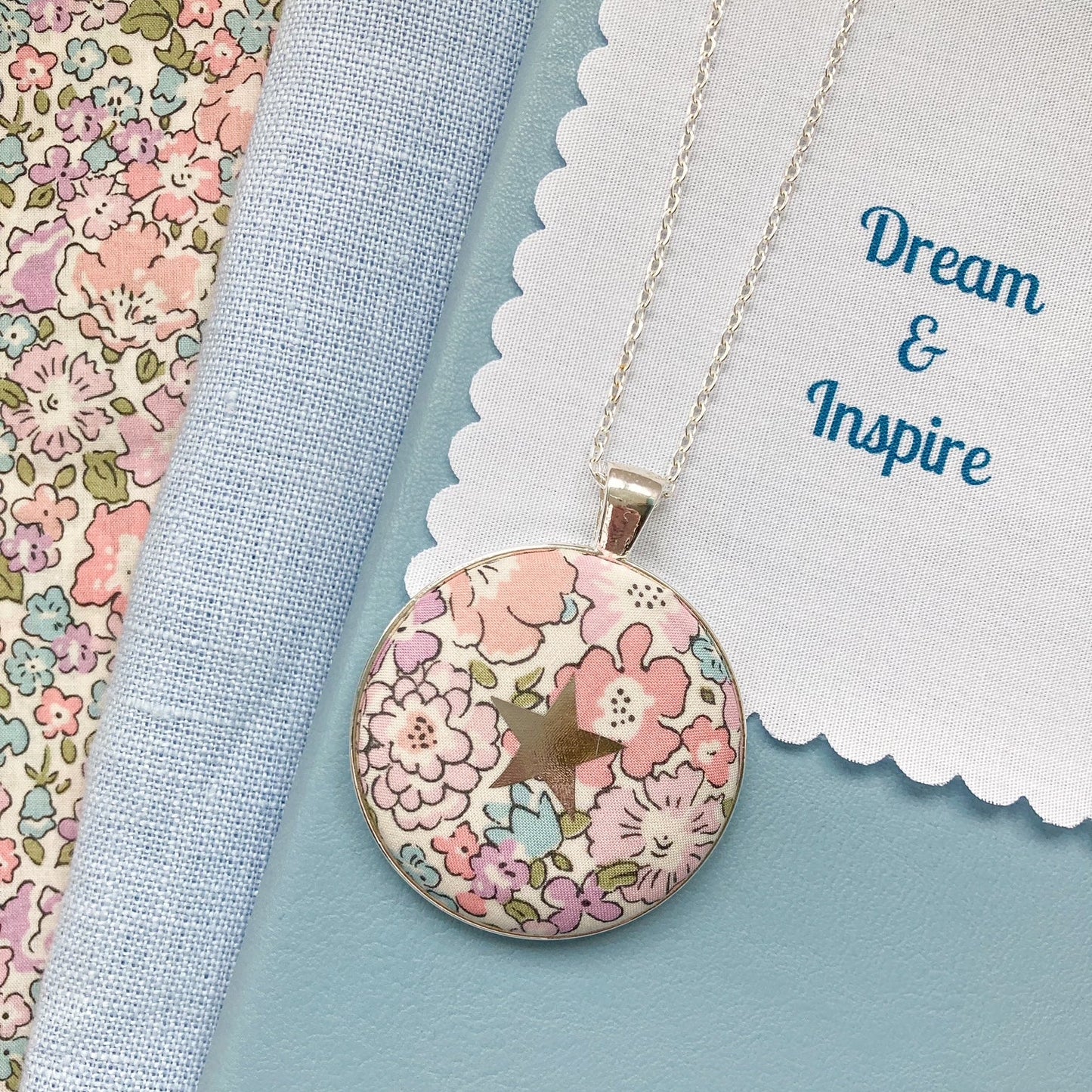 Pink floral necklace with a star design and a fabric message saying "Dream & Inspire"