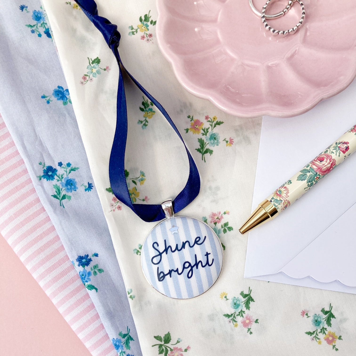 Keepsake with the words Shine Bright printed on blue and white striped fabric with a navy blue ribbon