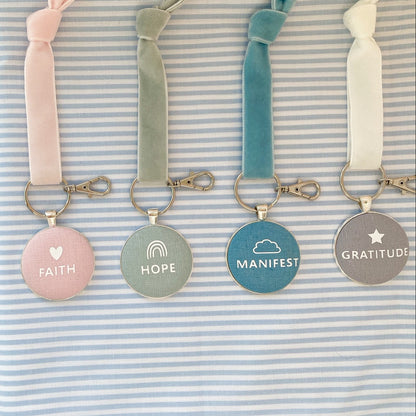 Set of keyrings with motivational phrases on a striped fabric background