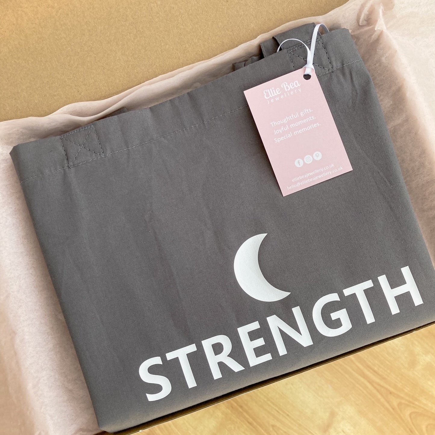 Grey Strength tote bag wrapped in tissue paper in a mailing box