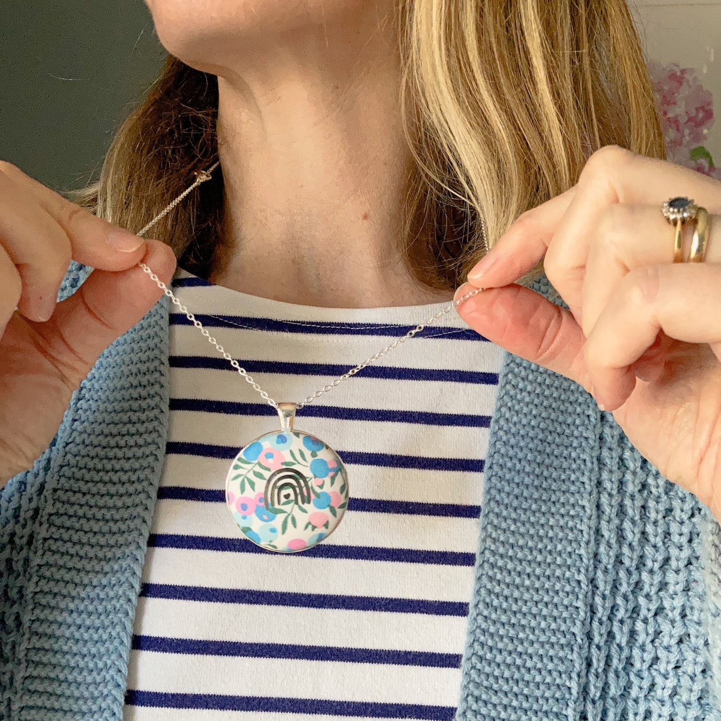 Person holding a necklace with a floral pendant