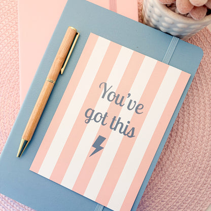 Pink and white striped postcard with You've Got This written in blue with a blue lightning symbol