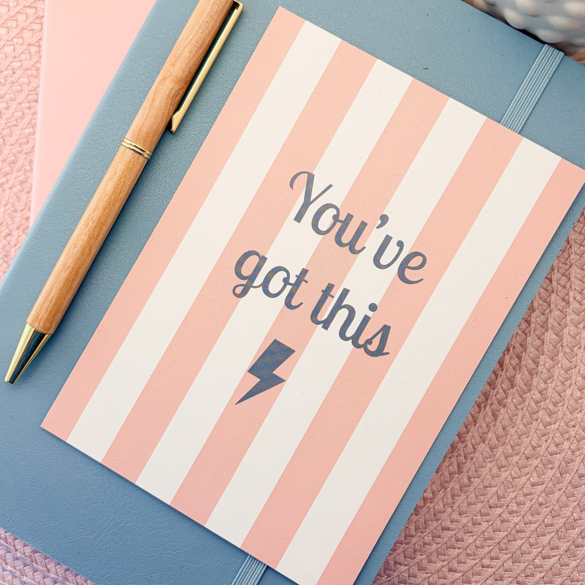Pink and white striped postcard with You've Got This written in blue with a blue lightning symbol
