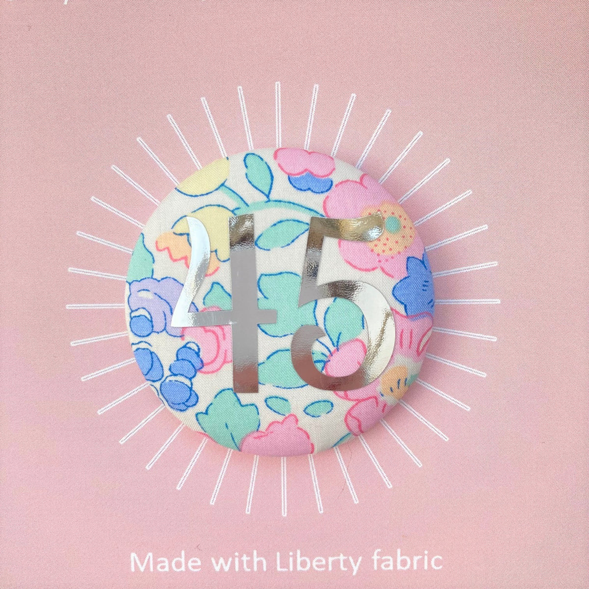 A fabric pink floral birthday badge printed with the number 45 in silver foil, on a Happy birthday postcard.